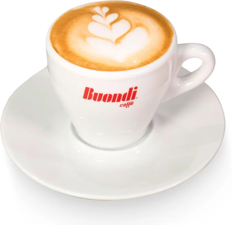A cappuccino with latte art in a white cup and saucer