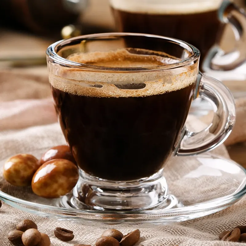 Espresso in a glass cup on a linen cloth with coffee beans