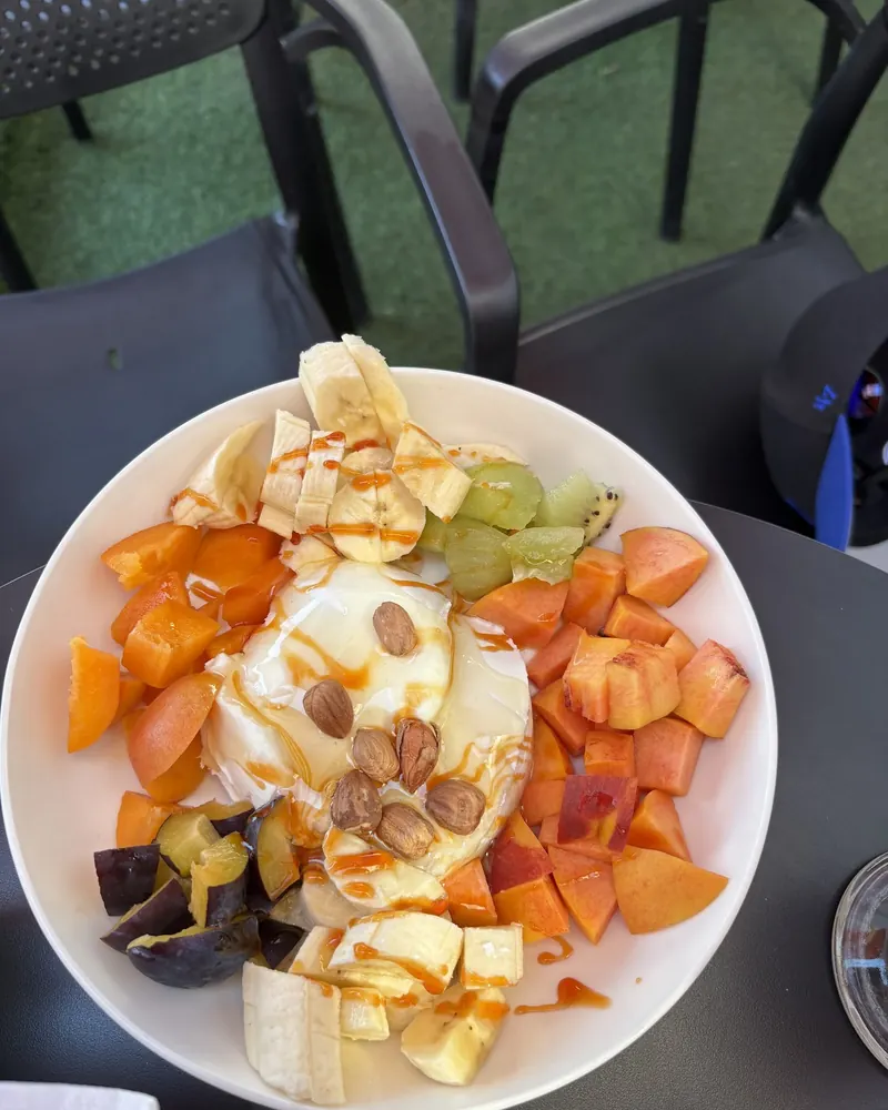 A bowl of yogurt with peaches, banana, almonds and honey