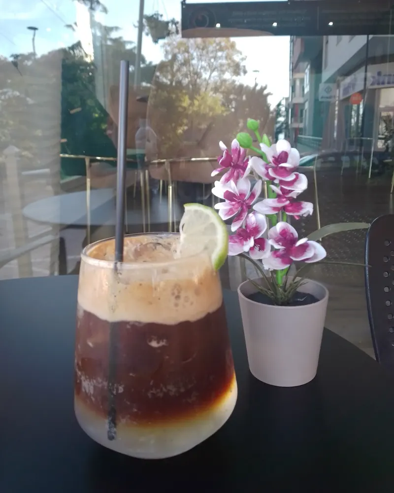 Iced coffee on the terrace table, with a lime slice and a small orchid