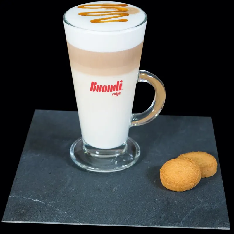 A layered latte in a tall glass with two biscuits
